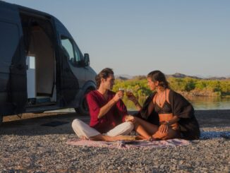 Coppia seduta accanto a un camper durante una sosta nella natura