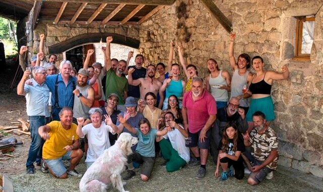 Volontariato e scambio di ospitalità in Francia in una fattoria dell’Ardèche, con gruppo di partecipanti davanti a un edificio rurale in pietra