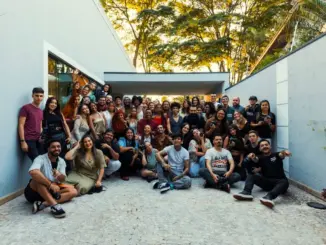 Grande gruppo di persone riunito all'aperto in un cortile alberato