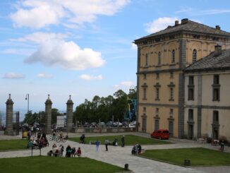 Cortile del Santuario di Oropa con edifici storici, visitatori e cielo azzurro in Piemonte